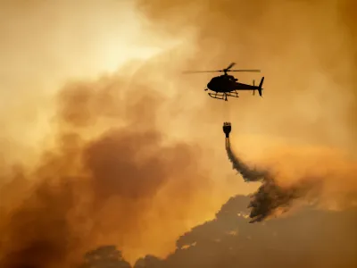 helicopter dumping water on forest fire (orange sky)